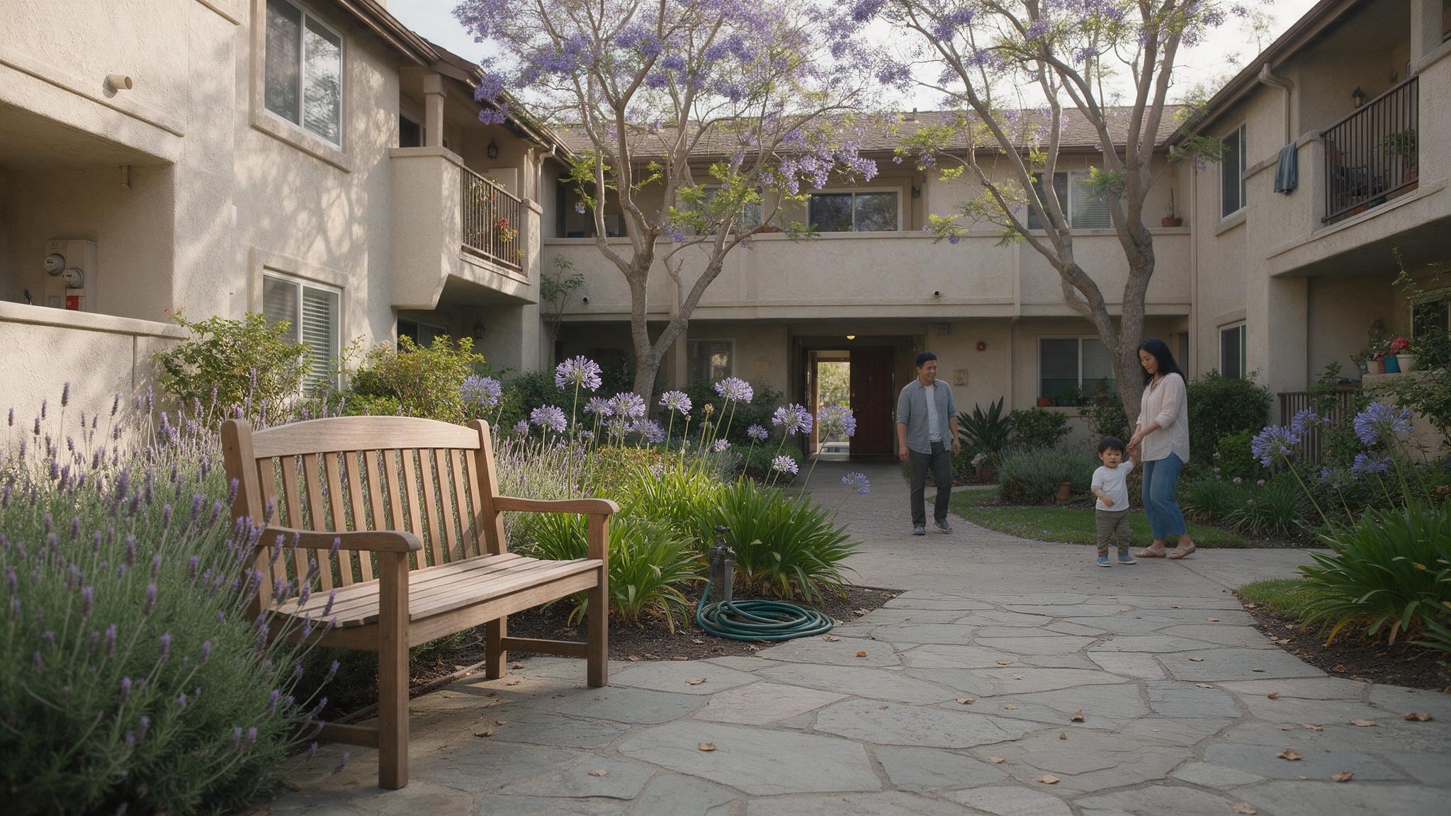 Sunny courtyard with blooming trees and flowers surrounded by residential buildings.