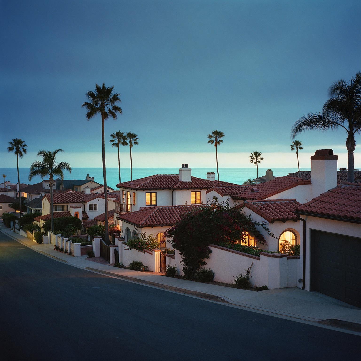 Spanish-style homes and palm trees above the Pacific in a San Diego County neighborhood at dusk